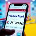 Смартфон с экраном Яндекс Маркет и промокодом ZFW9856 на фоне корзины с товарами